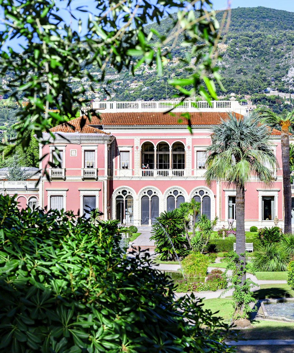 Villa Belle Époque rose des hauteurs cannoises, parc méditerranéen et collines à l'arrière-plan